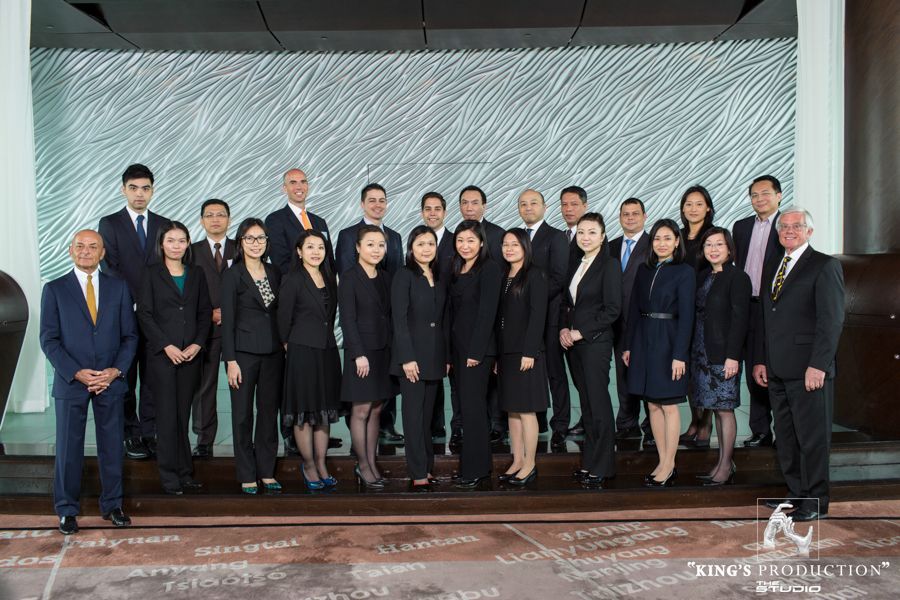 一群身著西裝的專業人士在一面有紋理的牆壁前擺姿勢。