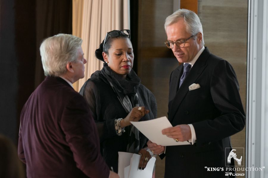 三位身著商務裝的人正在審閱文件。兩名男子和一名女子，室內，自然光。