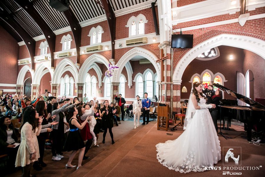 婚禮在一座紅磚教堂舉行。新郎新娘在台上擁抱，賓客們在一旁觀看。