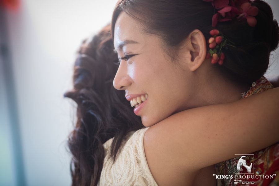 亞洲女子微笑著擁抱某人。她頭戴紅花，燈光溫暖。