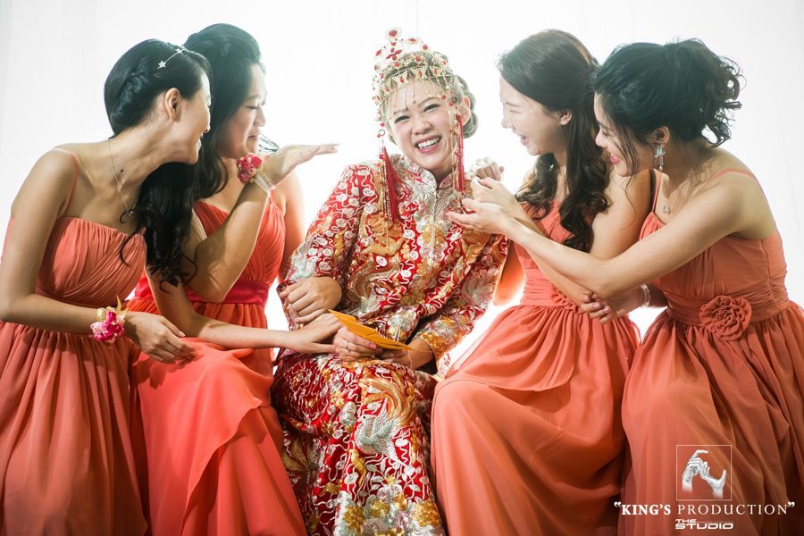新娘身著華麗的紅色禮服，周圍是身著珊瑚色禮服的伴娘，在工作室裡歡聲笑語。