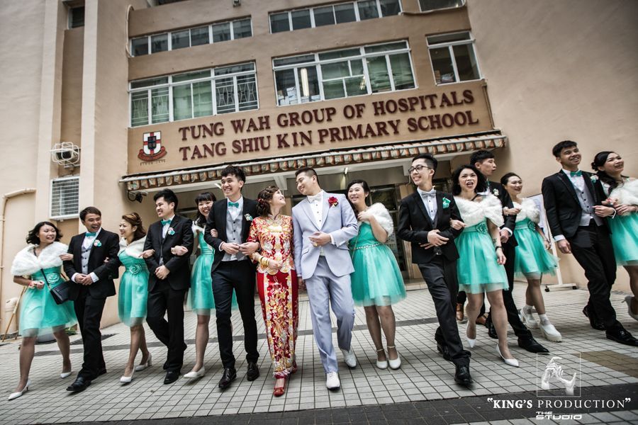 學校門前舉行婚禮。新郎新娘在伴娘/伴郎的簇擁下，微笑著向前走去。