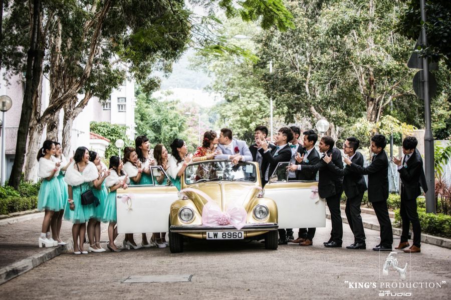婚禮上，新郎和新娘乘坐一輛黃色的老式汽車，周圍是身穿綠松石色衣服的伴娘和身穿黑色西裝的伴郎。