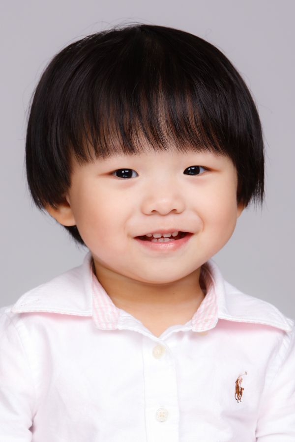 微笑的小孩，黑髮，穿著白領襯衫。