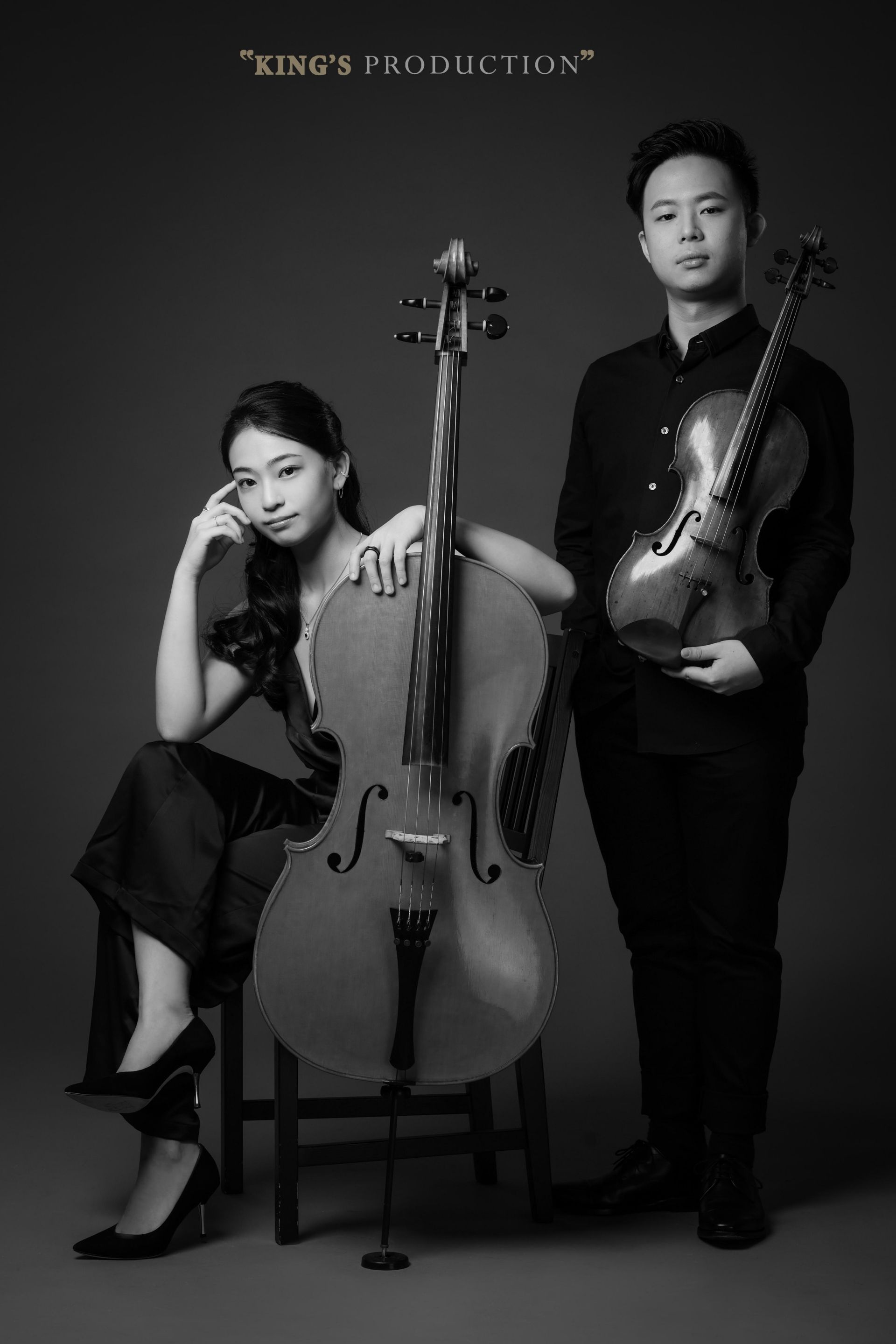 兩位音樂家，一位坐著的大提琴手和一位站著的小提琴手，正在工作室裡擺姿勢拍攝單色肖像。