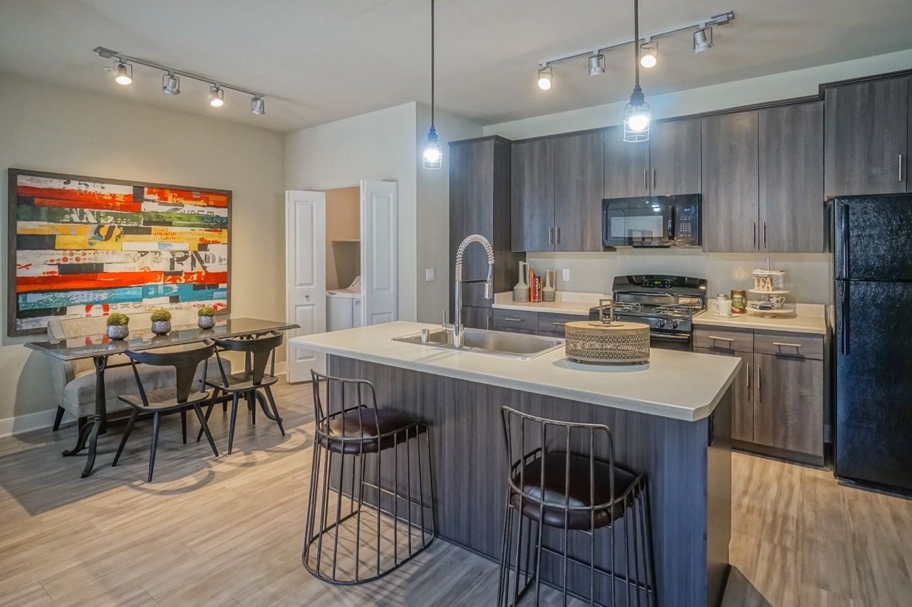 Open-concept kitchen with an island, grey wood cabinets, and pendant lights.