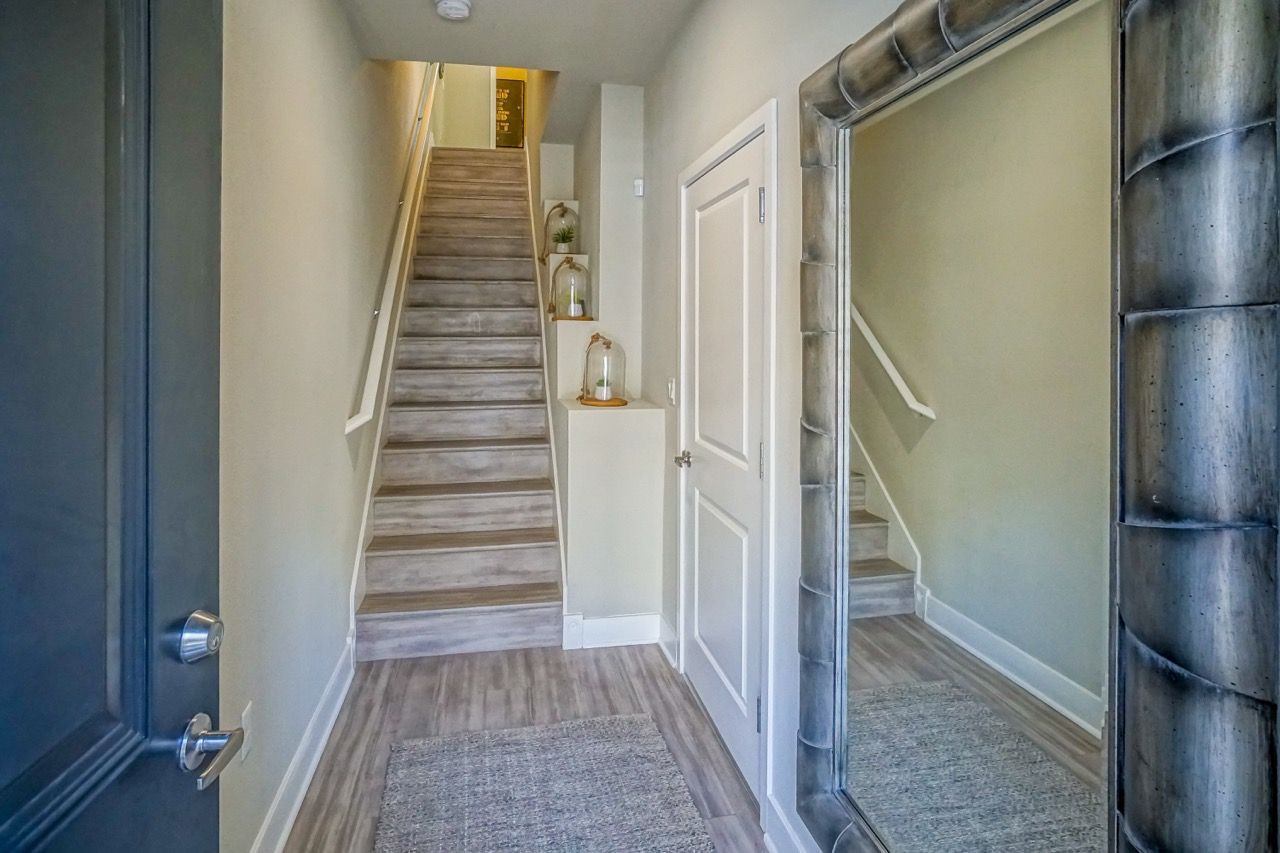 Interior apartment entry with stairs, a white door, and a large mirror.