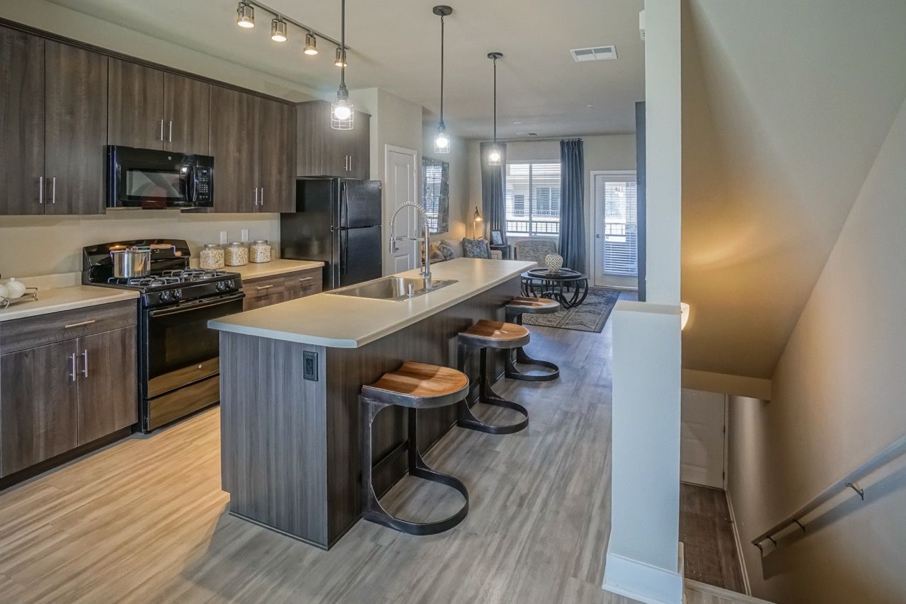 Open-concept kitchen with dark wood cabinets, stainless appliances, and a long island with seating.