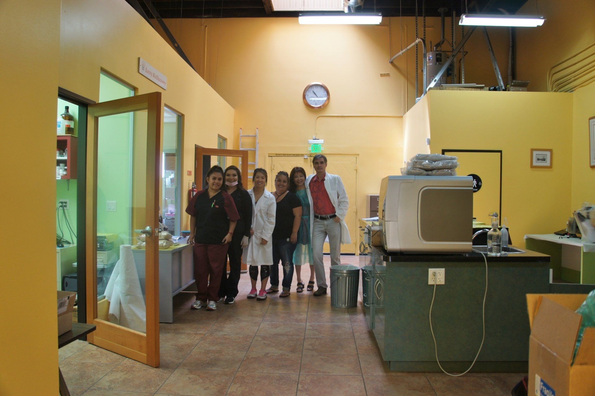 Group of people standing in a yellow lab; some are wearing medical scrubs.