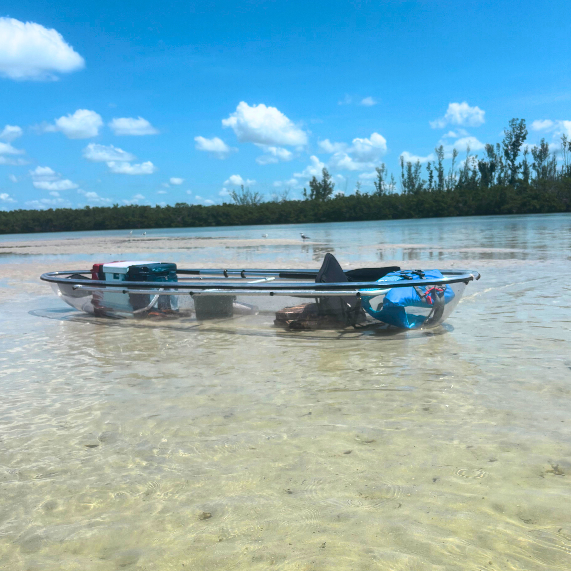 Clear kayak sitting in shallow water.
