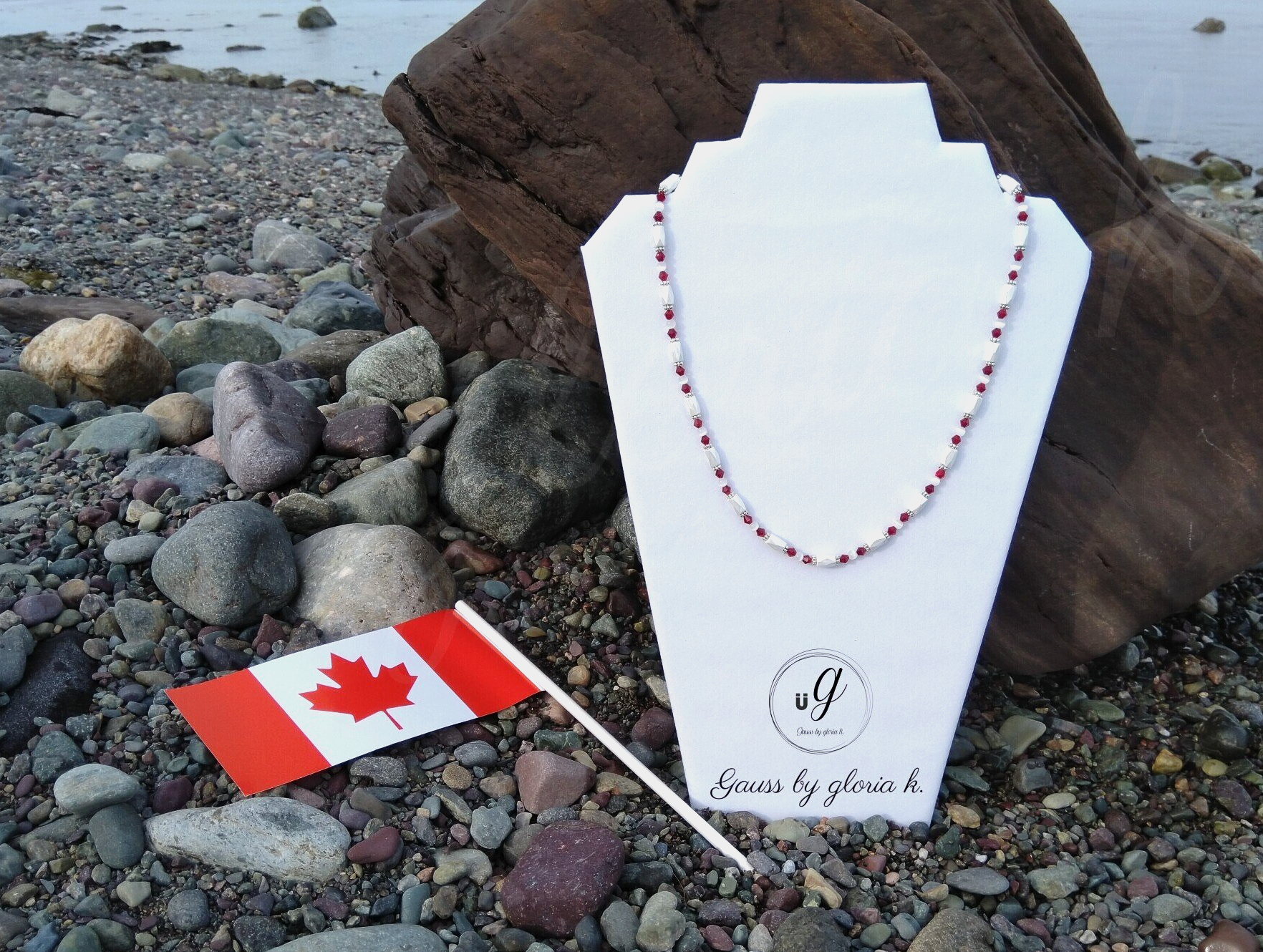 Canadian flag magnetic hematite necklace on rocky Atlantic shoreline