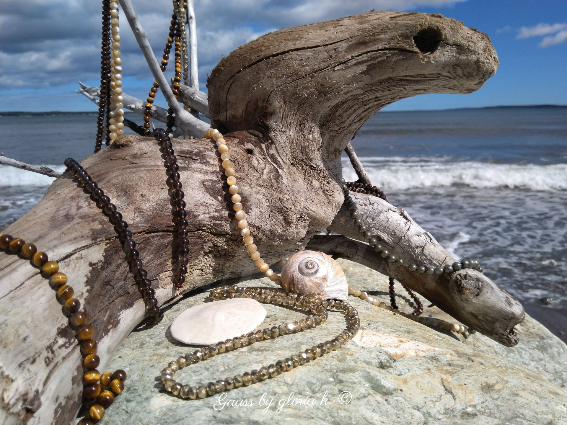 Two driftwood sea creatures with gemstones, crystals and sea shells, close up.