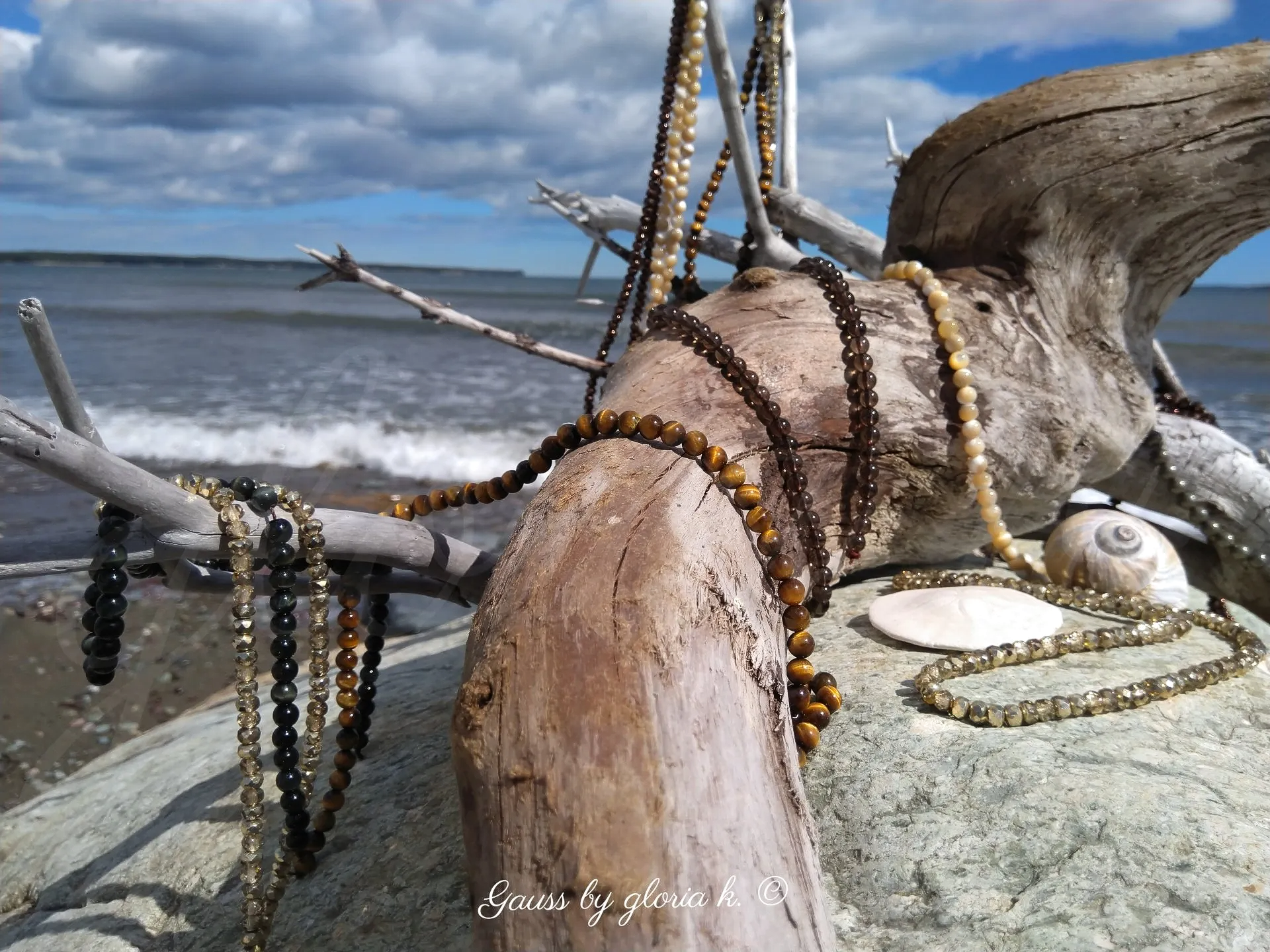 Driftwood sea creature draped with gemstones and crystals, close up.