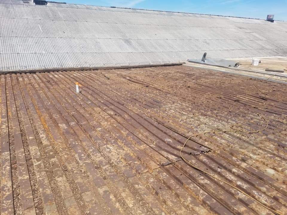 Corrugated metal roof with rusted metal strips in foreground and curved metal in background.