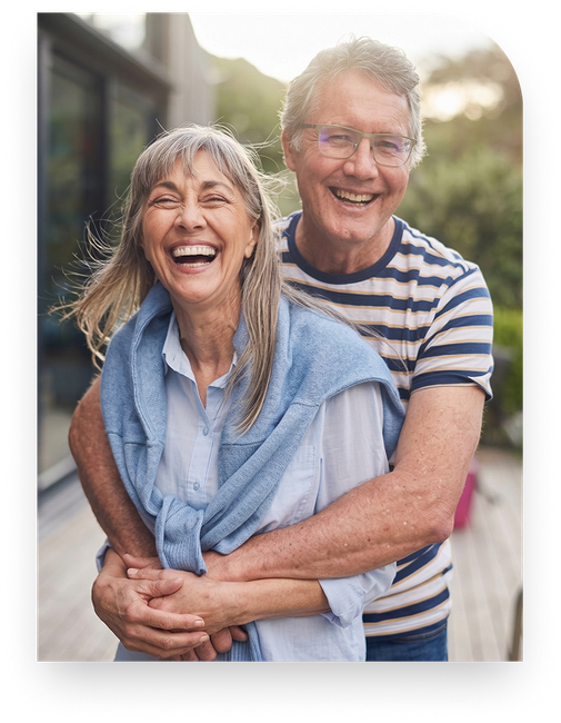 A joyful senior couple embracing and laughing together outdoors.