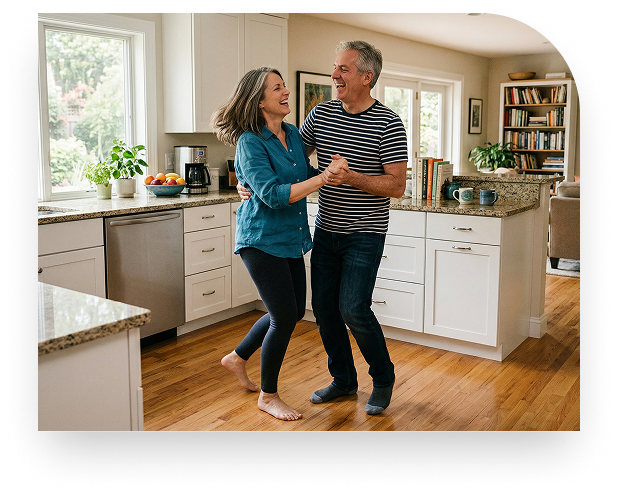 A happy senior couple dancing together in a bright kitchen.