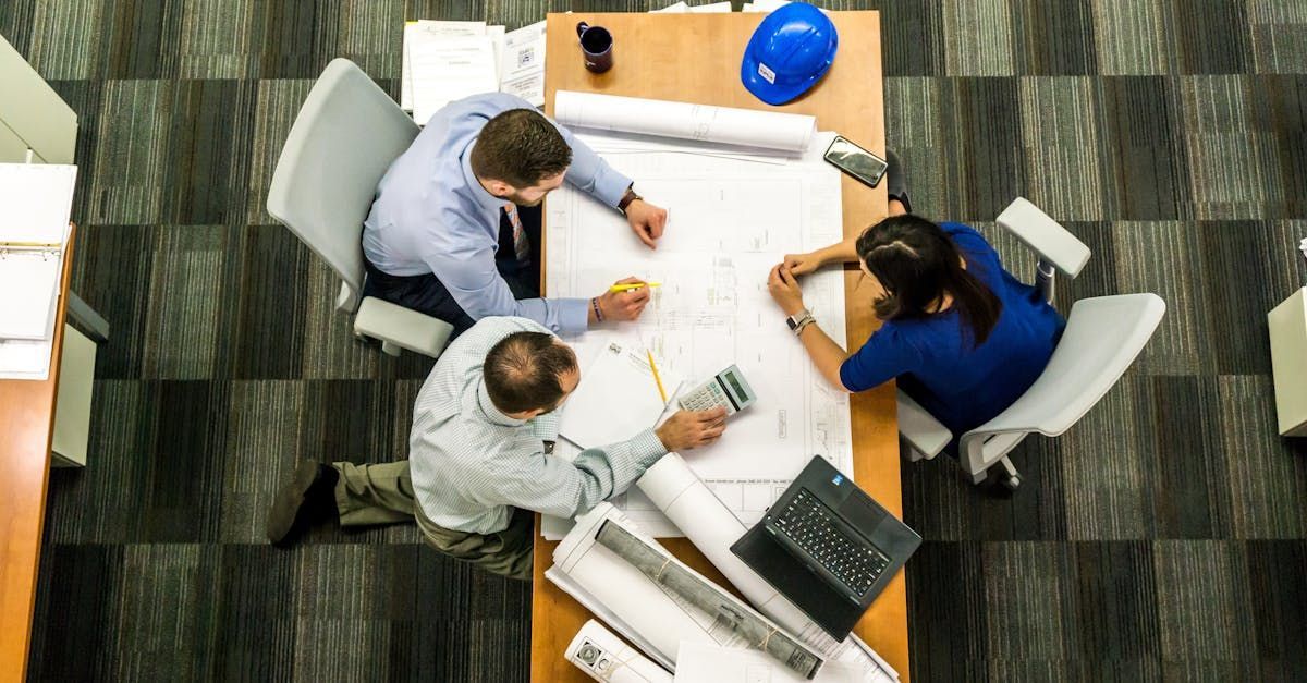 A group of people are sitting around a table looking at blueprints.