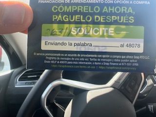 A person is holding a card in front of a car