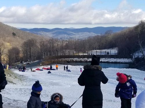 A group of people are sledding down a snow-covered hill - Hickory, NC - Giving Kids Hope Foundation 