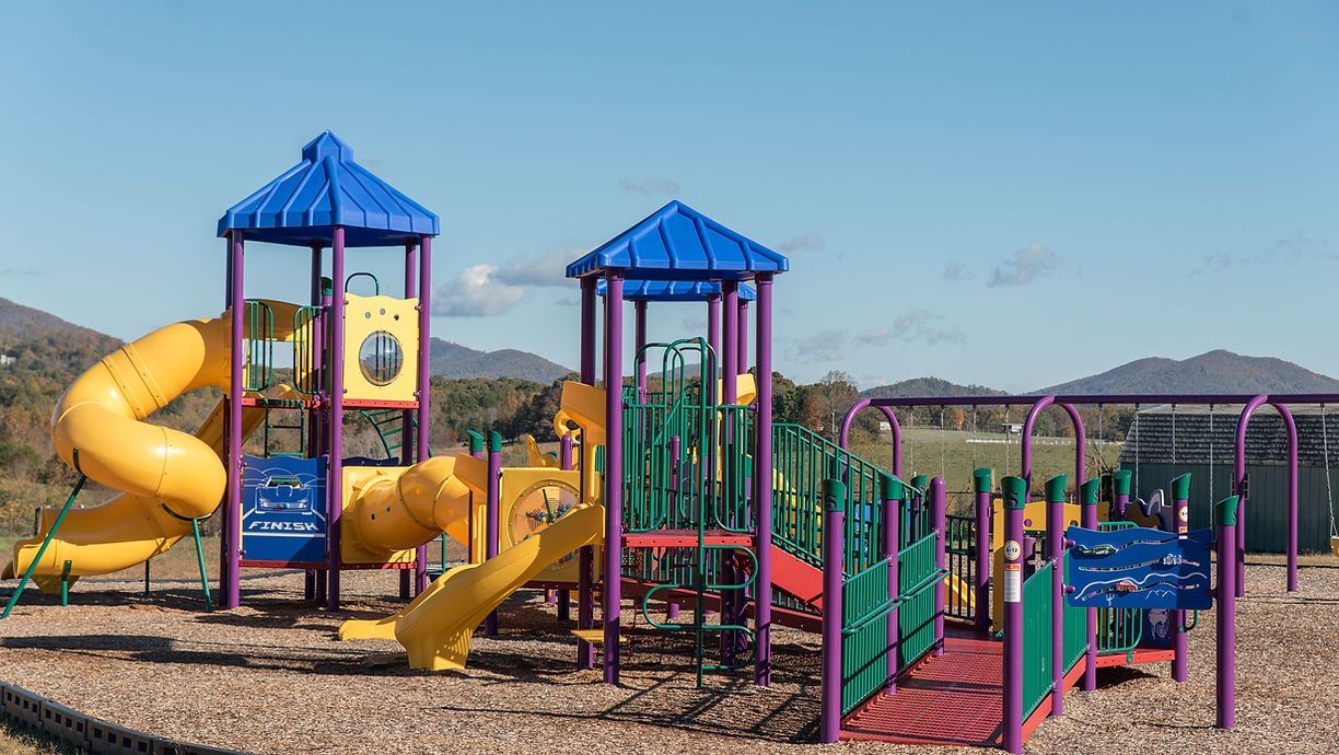 A colorful playground with a yellow slide and a purple slide - Hickory, NC - Giving Kids Hope Founda