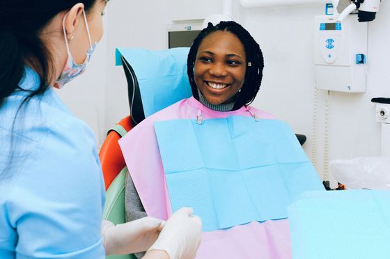 A woman is smiling while sitting in a dental chair