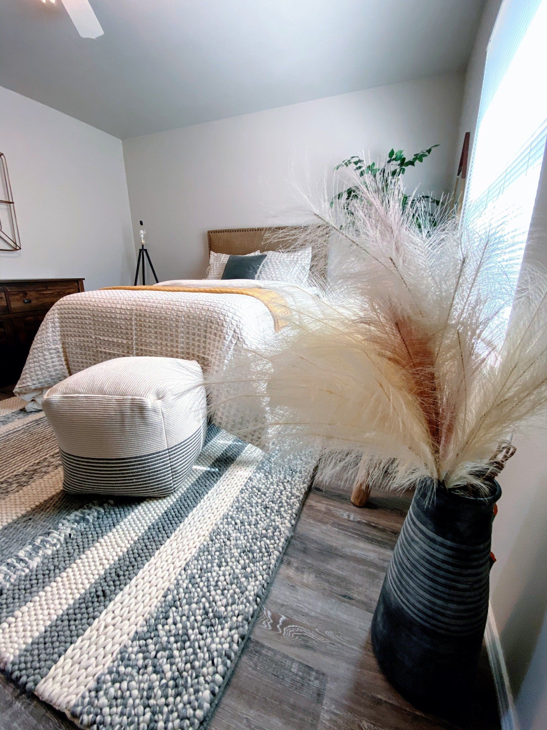 Bed in second bedroom with boho decor and pampas grass