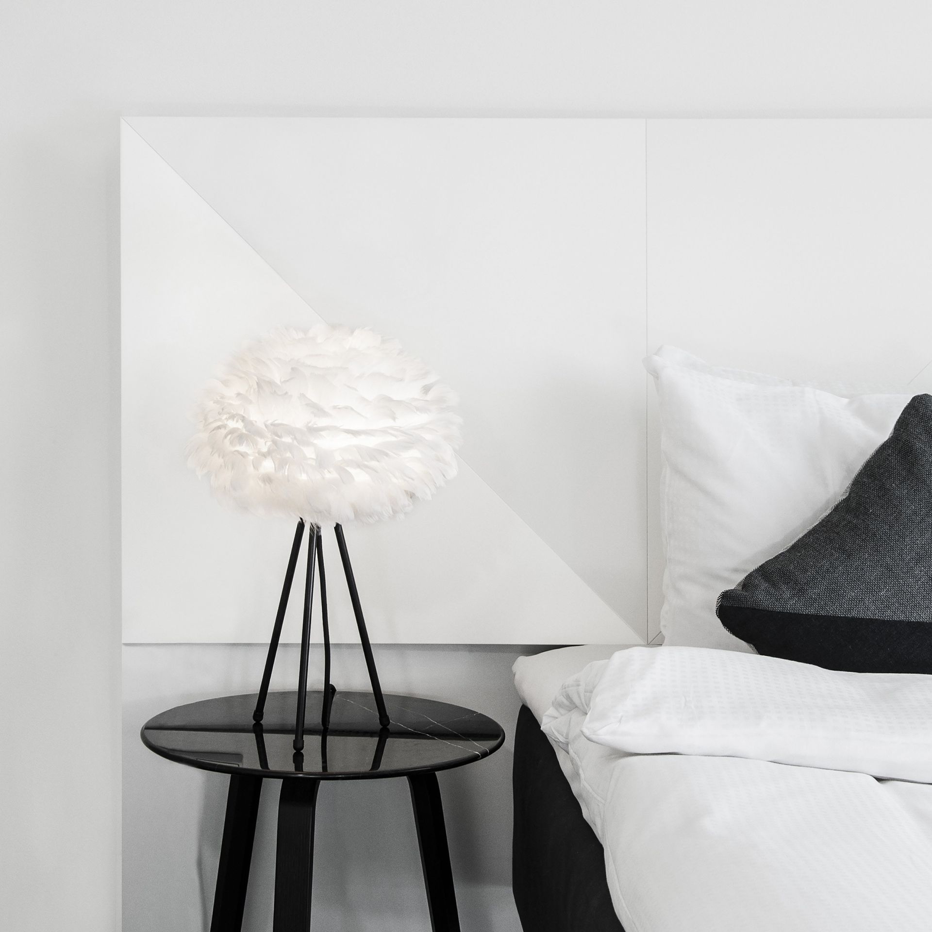 A bedroom with a bed and a table with a lamp on it