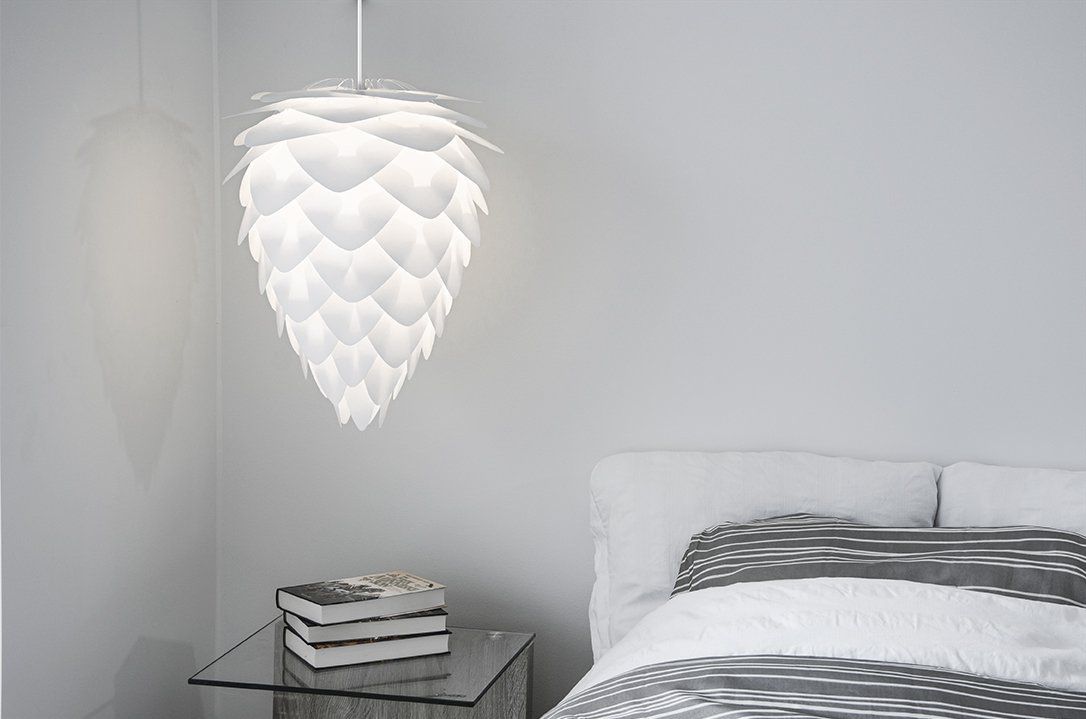 A bedroom with a bed and a lamp hanging from the ceiling.