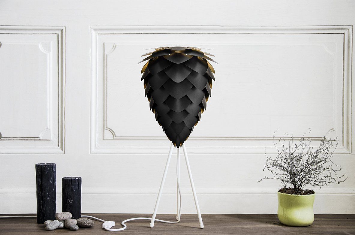 A black lamp is sitting on a wooden table next to a potted plant.