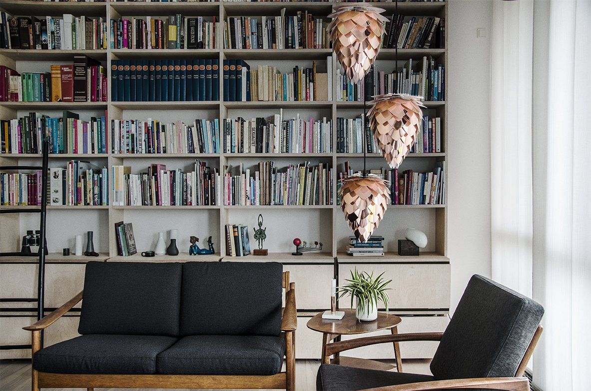 A living room with a couch and a chair in front of a bookshelf filled with books.
