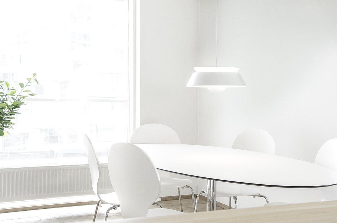 A dining room with a table and chairs in front of a window.