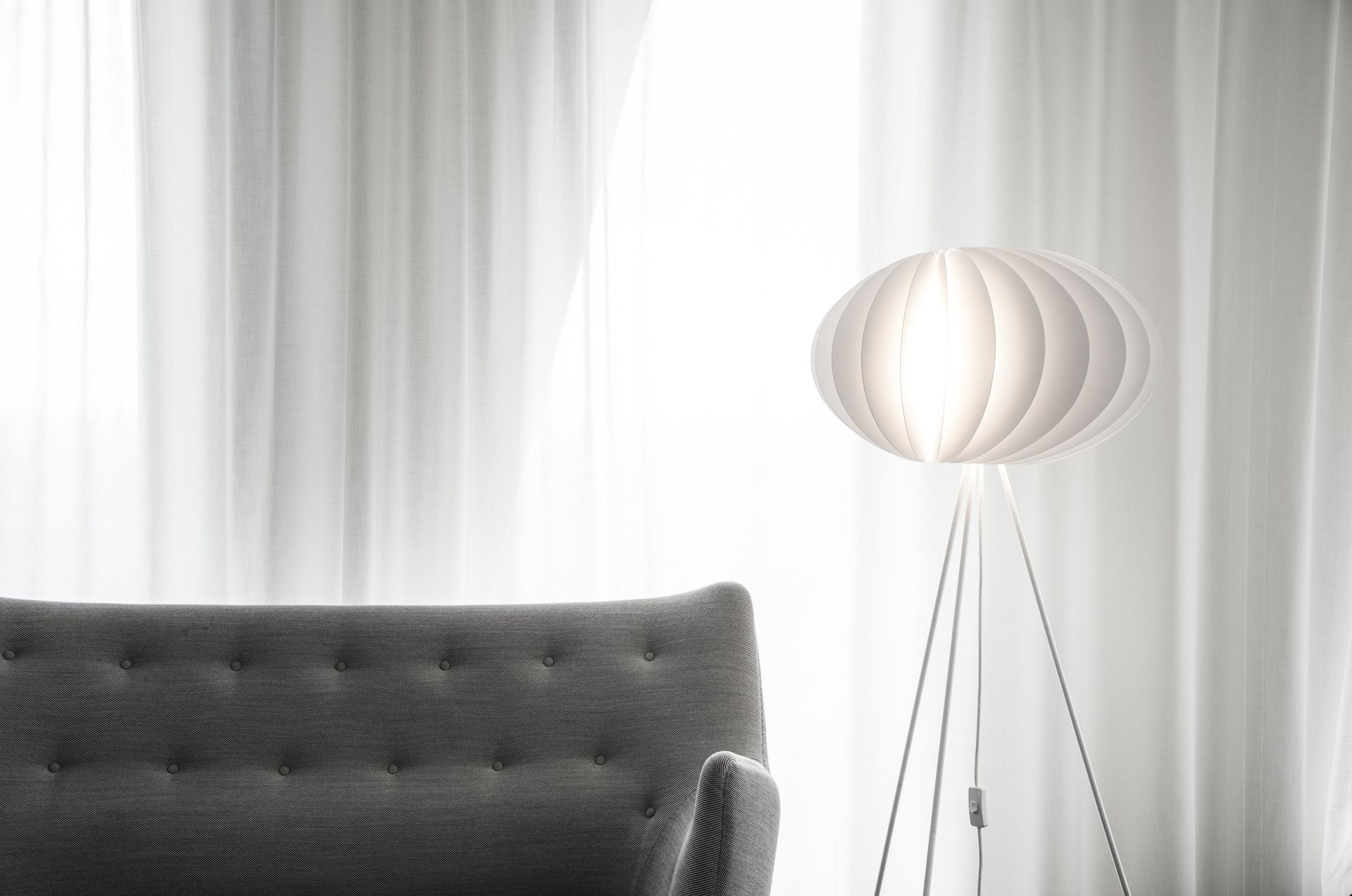 A black and white photo of a living room with a couch and a lamp.