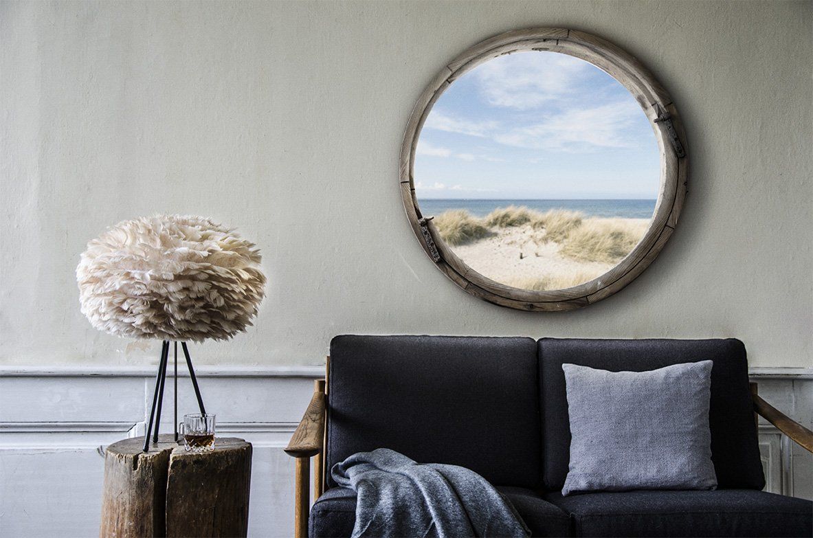 A living room with a couch and a round mirror on the wall.