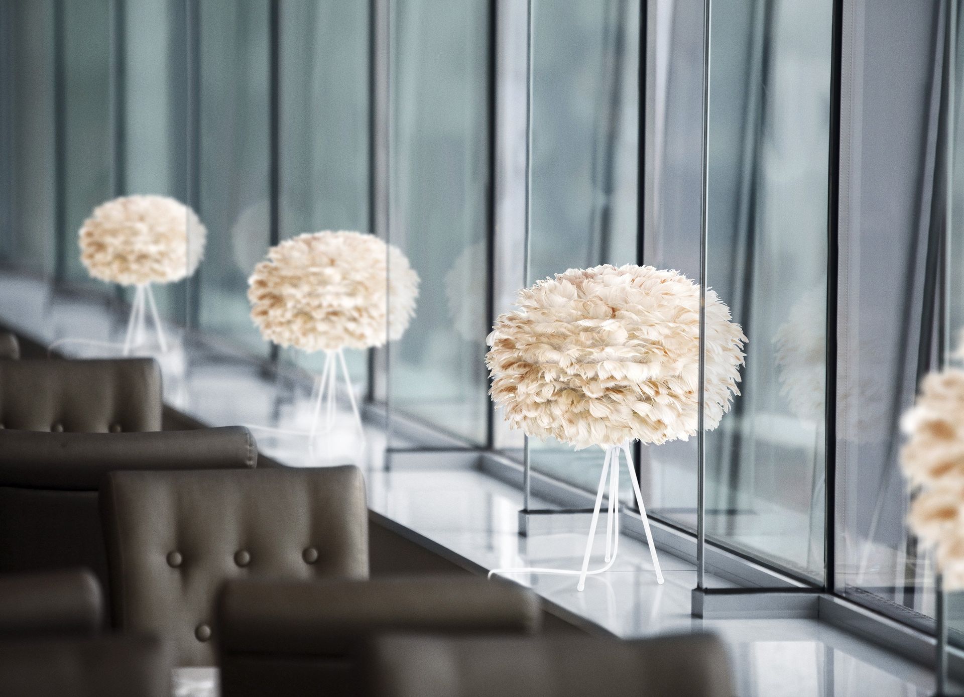 A row of feather lamps are lined up in a room next to a window.