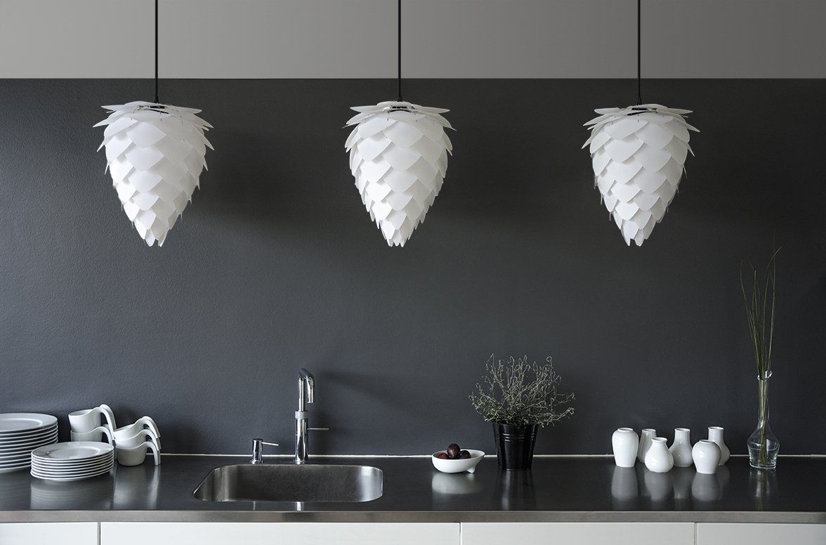 A kitchen with three white pendant lights hanging from the ceiling