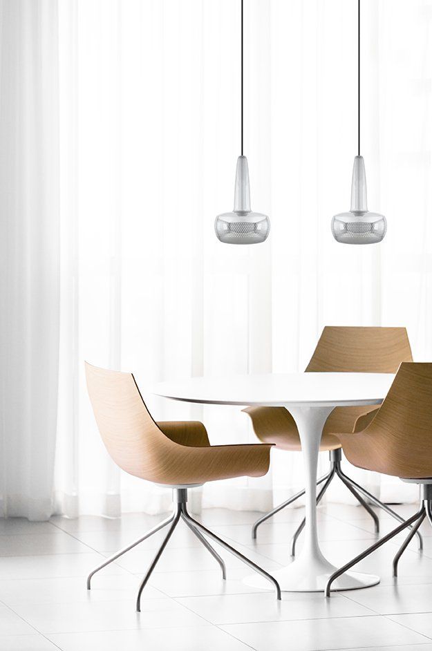 A dining room with a table and chairs in front of a window.