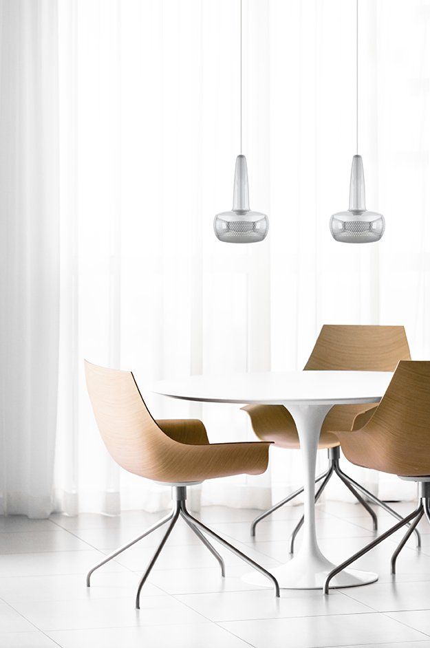 A dining room with a table and chairs in front of a window.