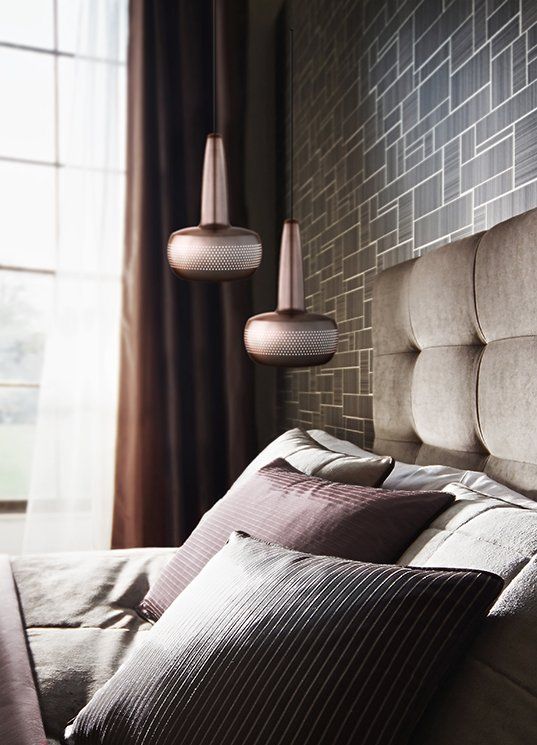 A bedroom with a bed and two lamps hanging from the ceiling
