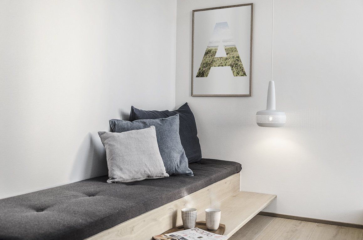 A living room with a couch , pillows and a picture on the wall.