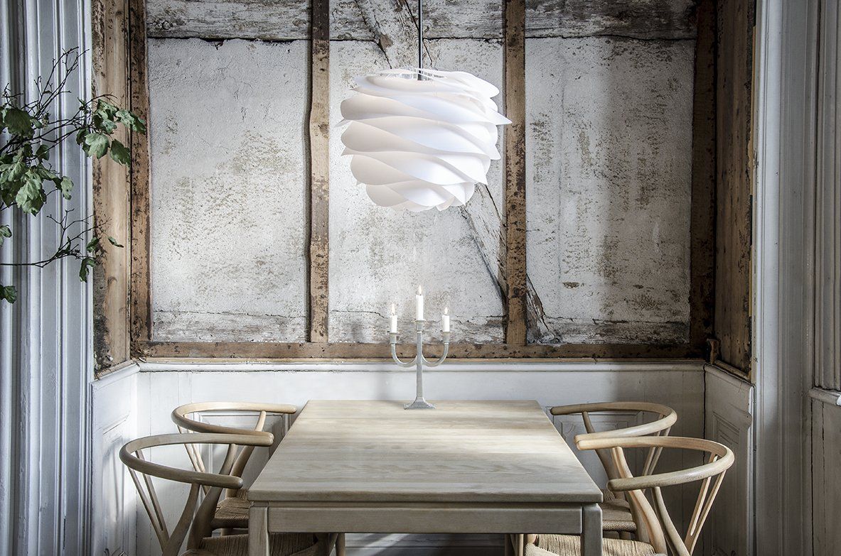 A dining room with a table and chairs and a light hanging from the ceiling.