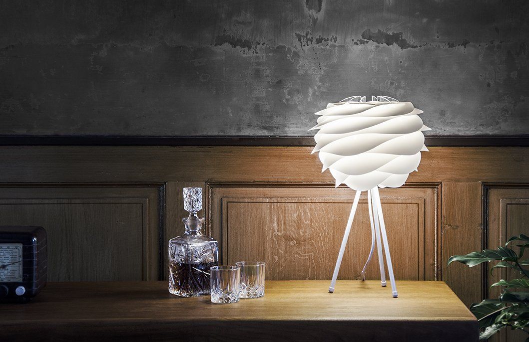 A lamp is sitting on a wooden table next to a decanter and glasses.