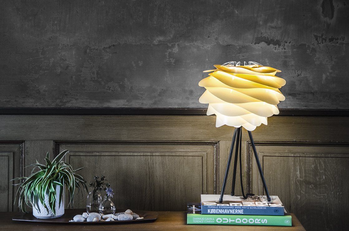 A lamp is sitting on top of a stack of books on a table.
