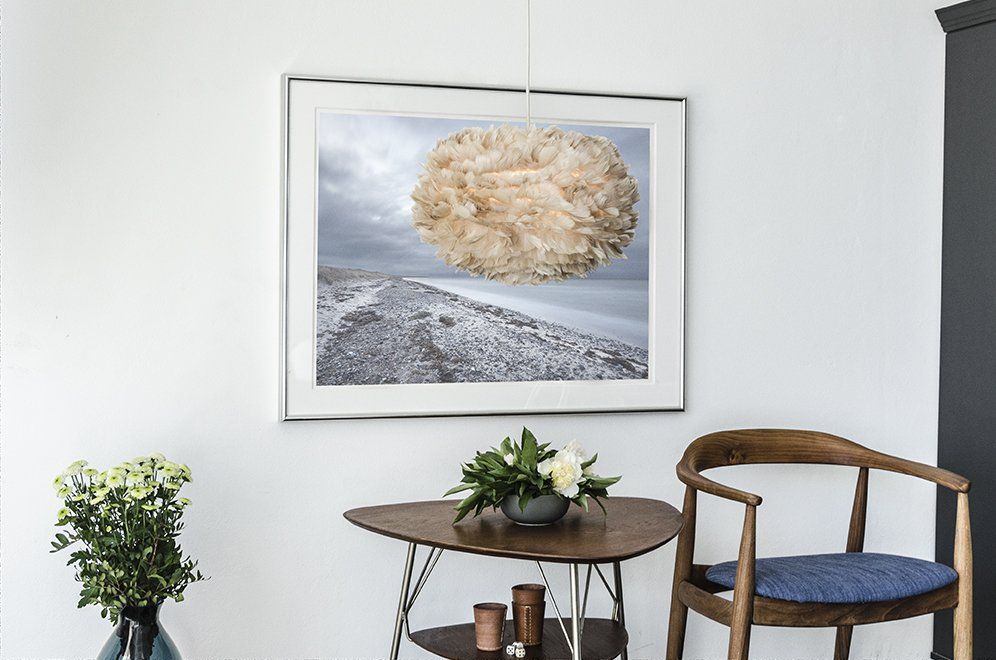 There is a picture on the wall above the table and chair.