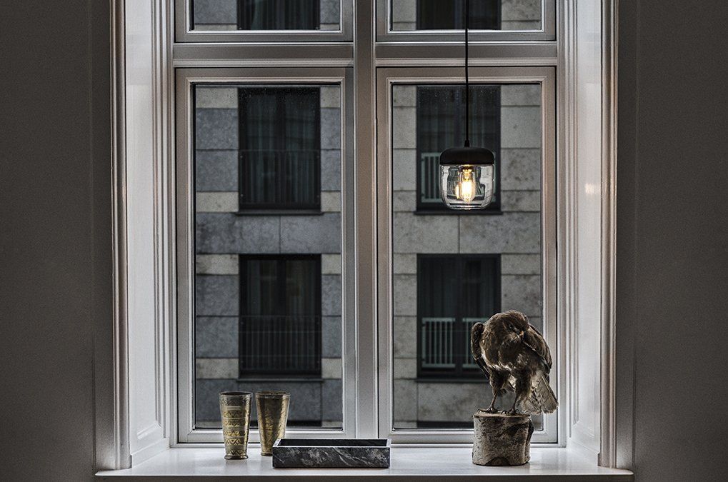 A window with a lamp hanging from it and a statue on a window sill.