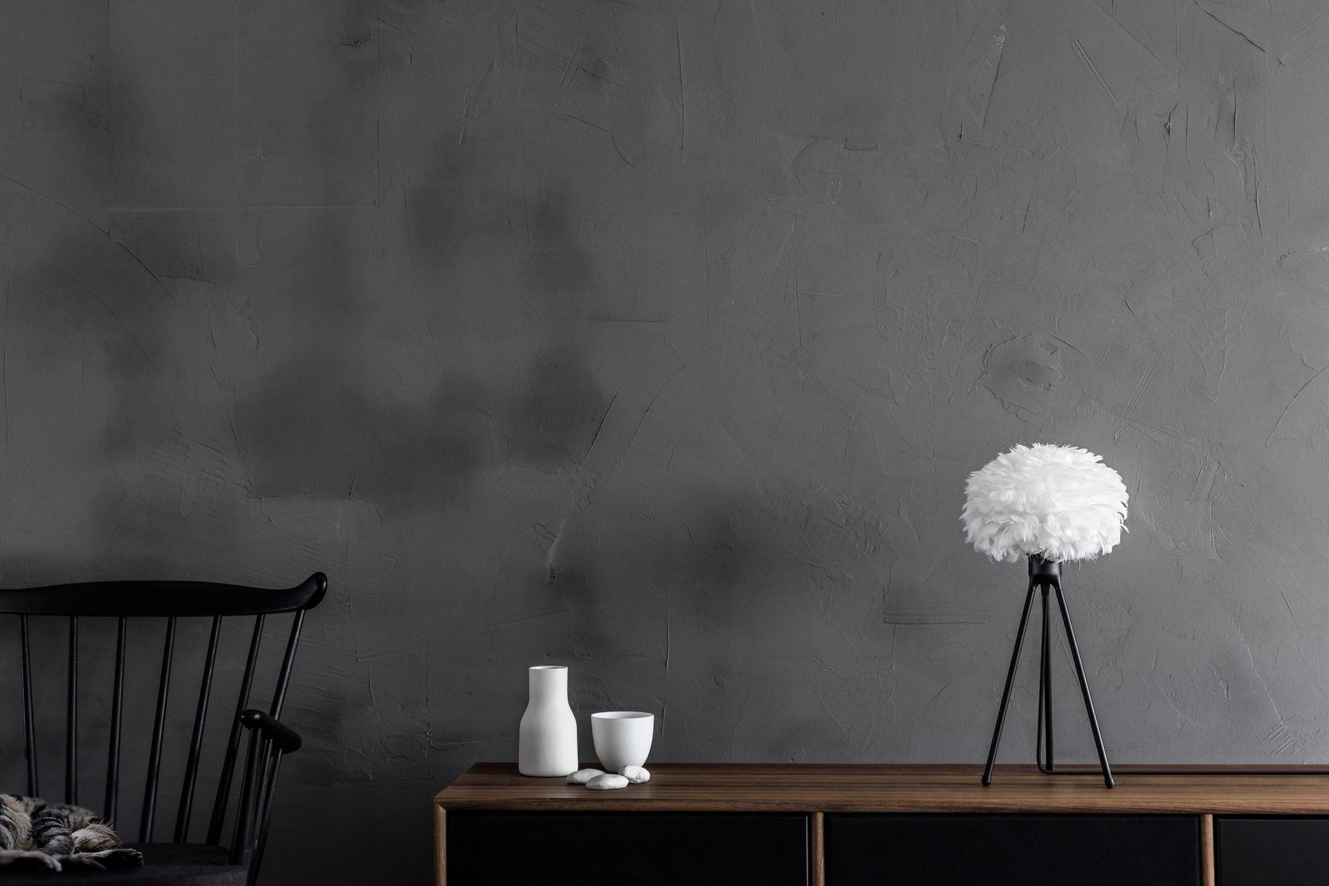 A table with a lamp and vases on it in a living room.