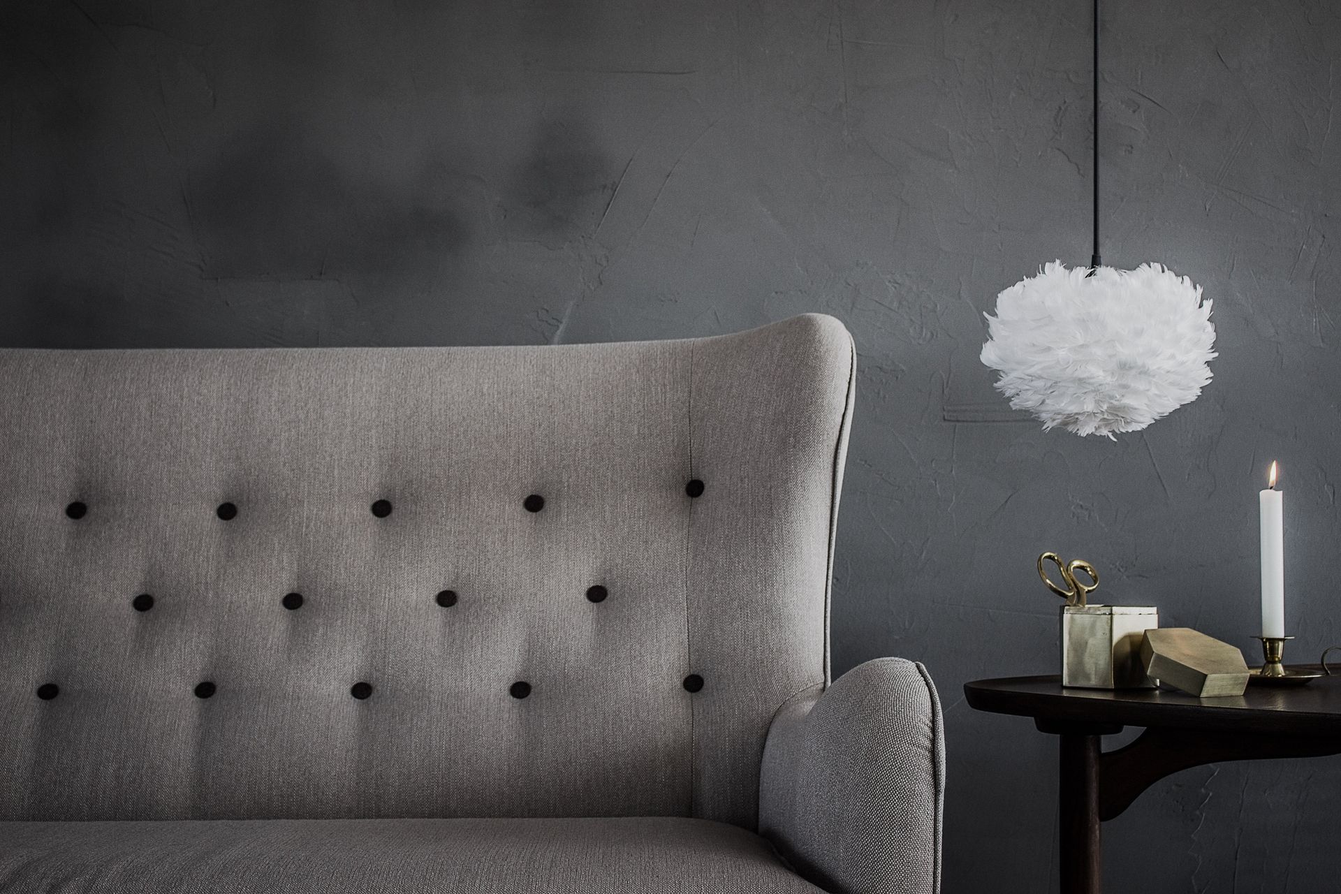 A living room with a couch and a table with a candle on it.