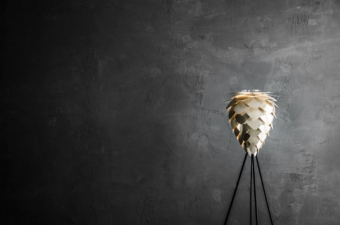A lamp is sitting on a tripod in front of a black wall.