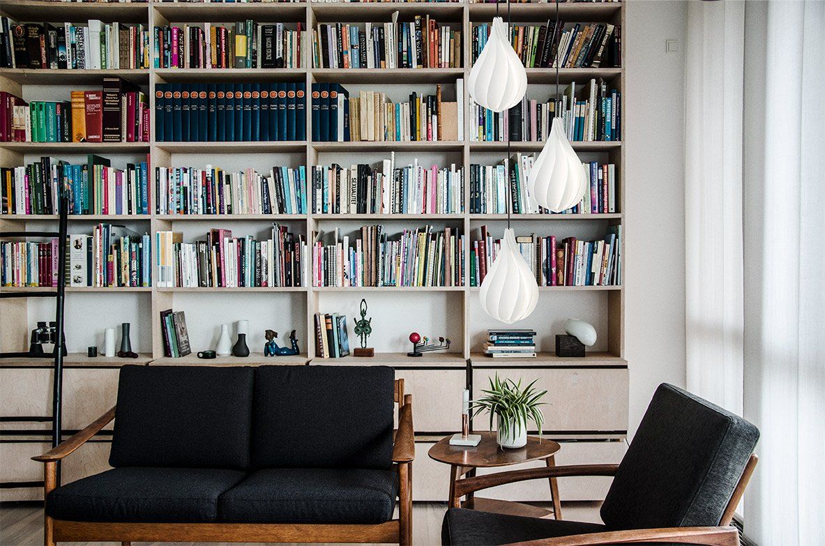 A living room with a couch and a chair in front of a bookshelf filled with books.