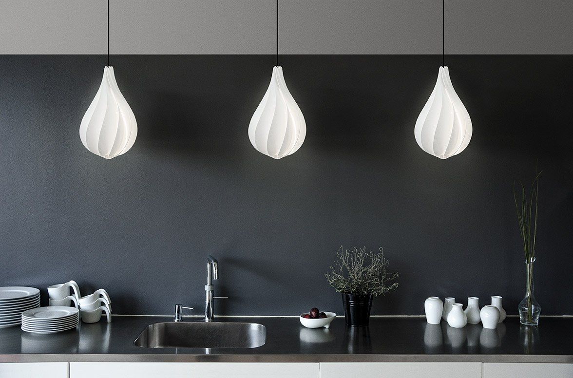 A kitchen with three white pendant lights hanging from the ceiling