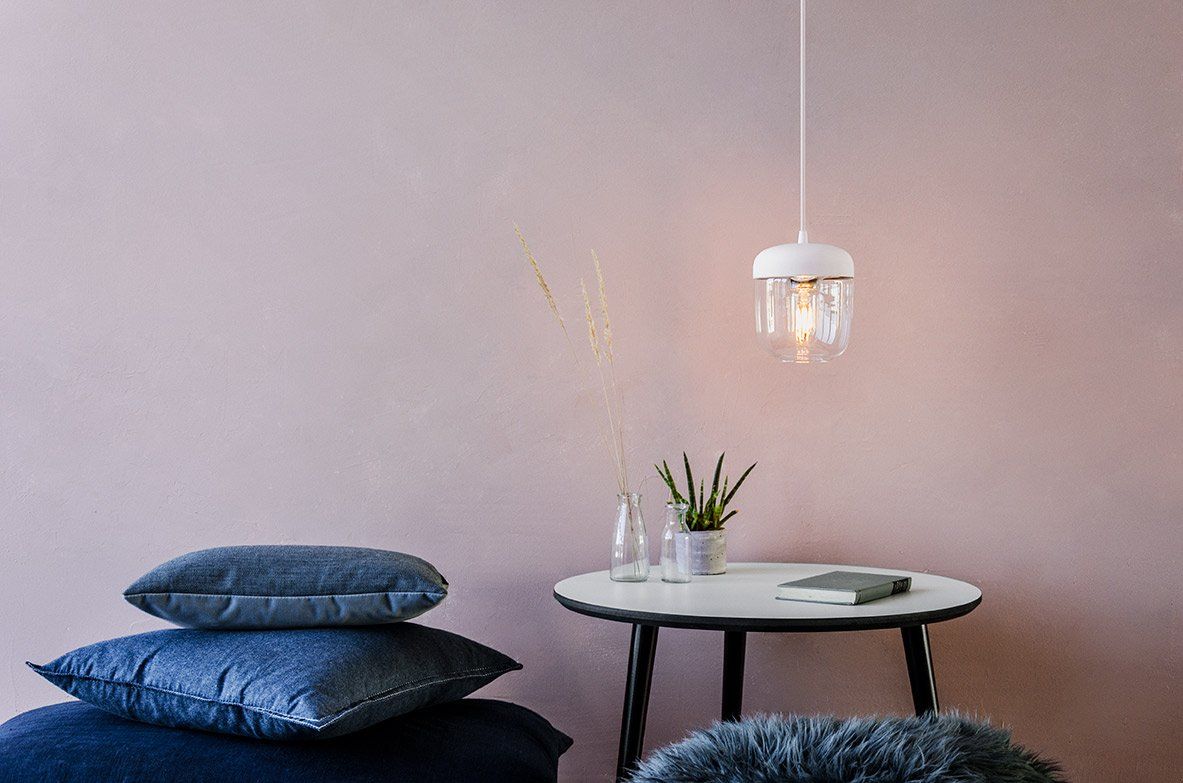 A living room with a table , pillows , and a pendant light.
